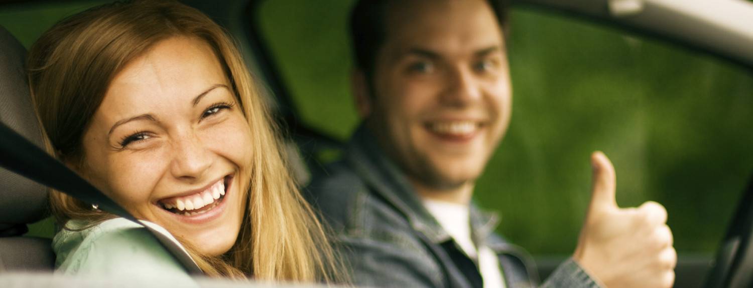 happy-couple-driving-thumbs-up